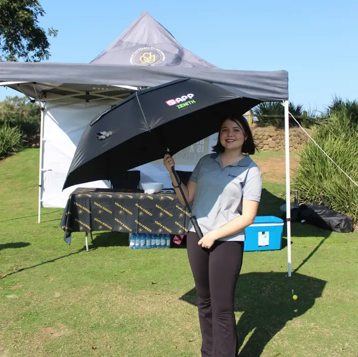Guest standing beneath a branded sponsor gazebo at the golf course.